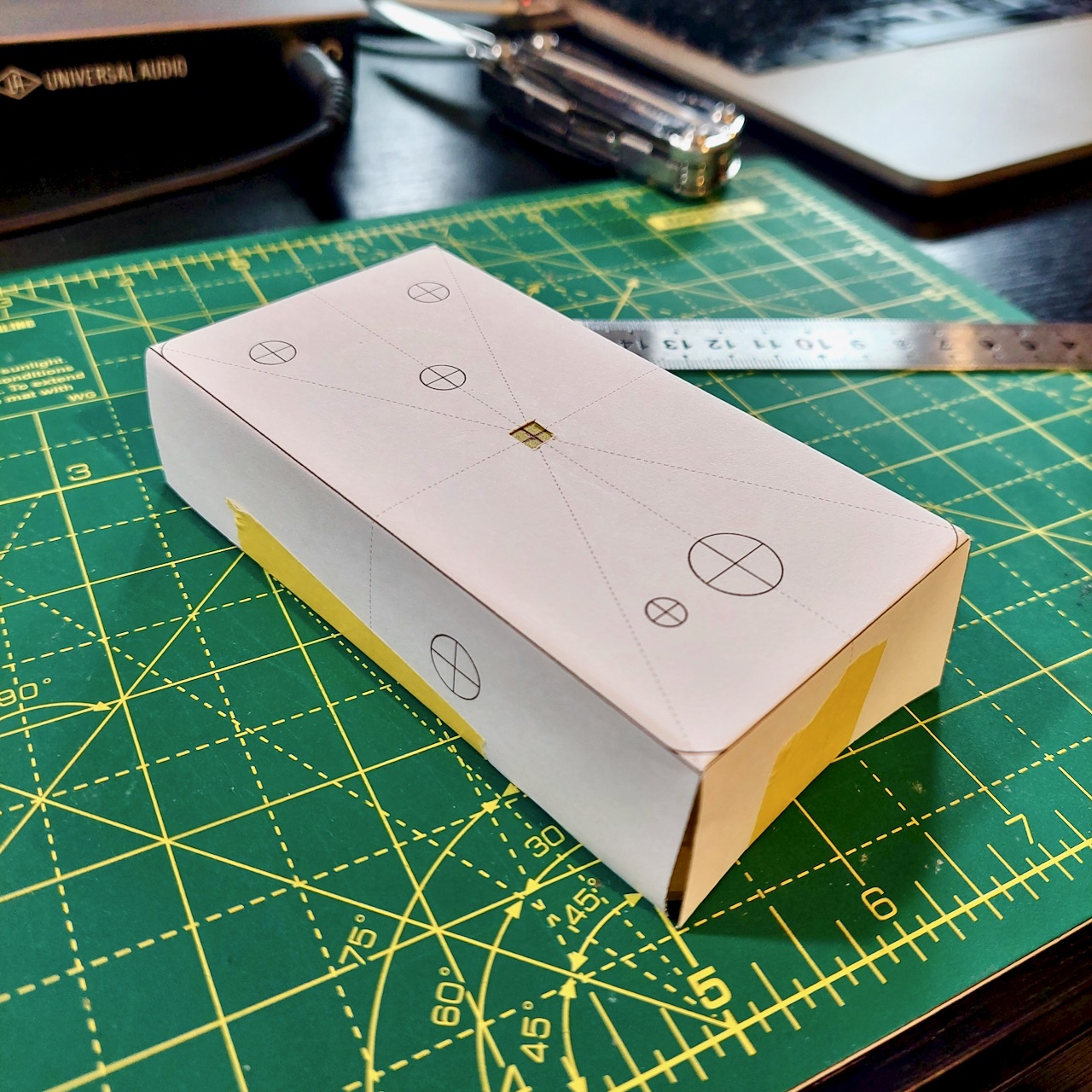 The drill template wrapped over an enclosure with its side panels folded down and taped to the walls.